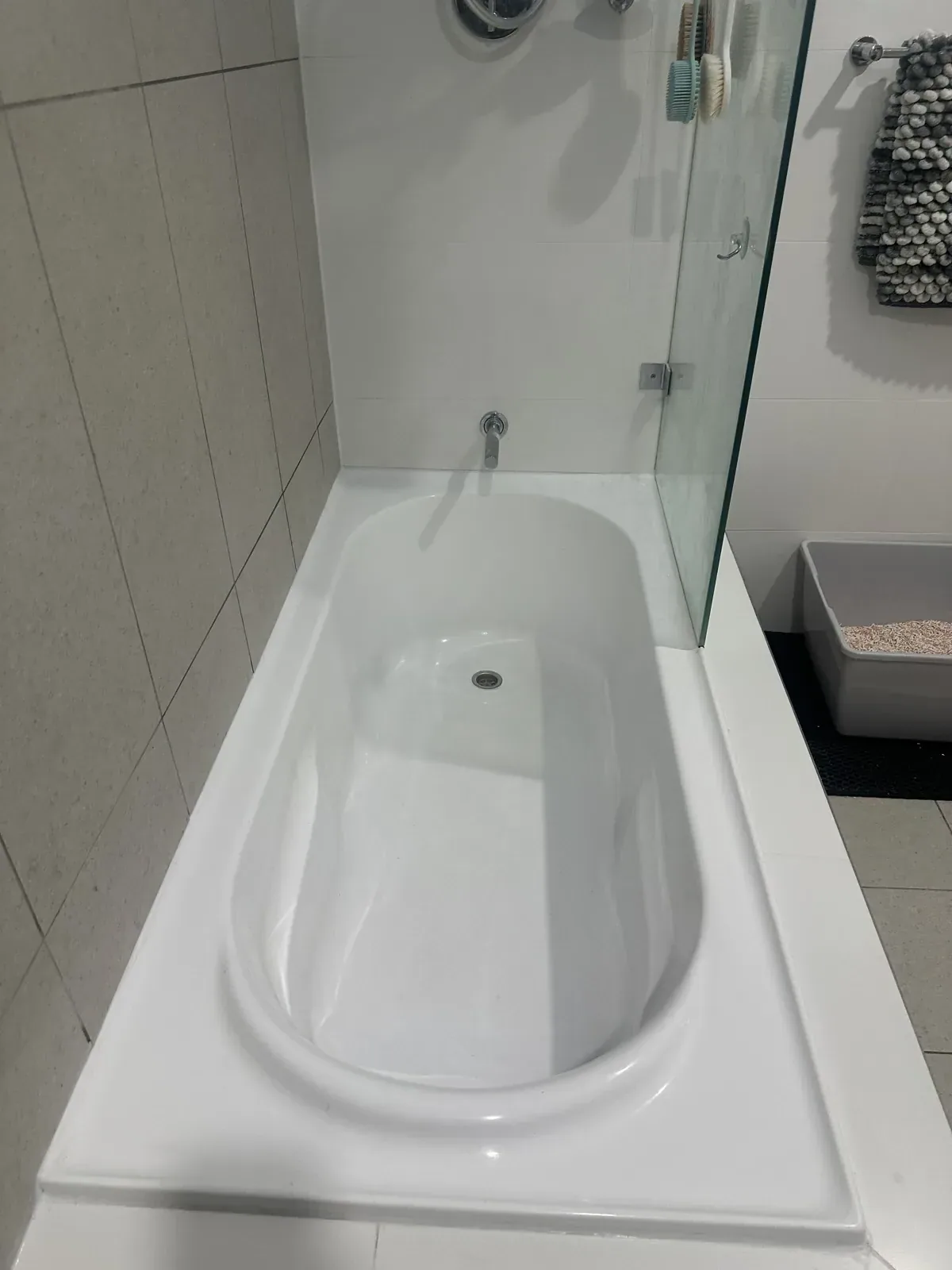 Sealed bath and over-bath shower in white tiles