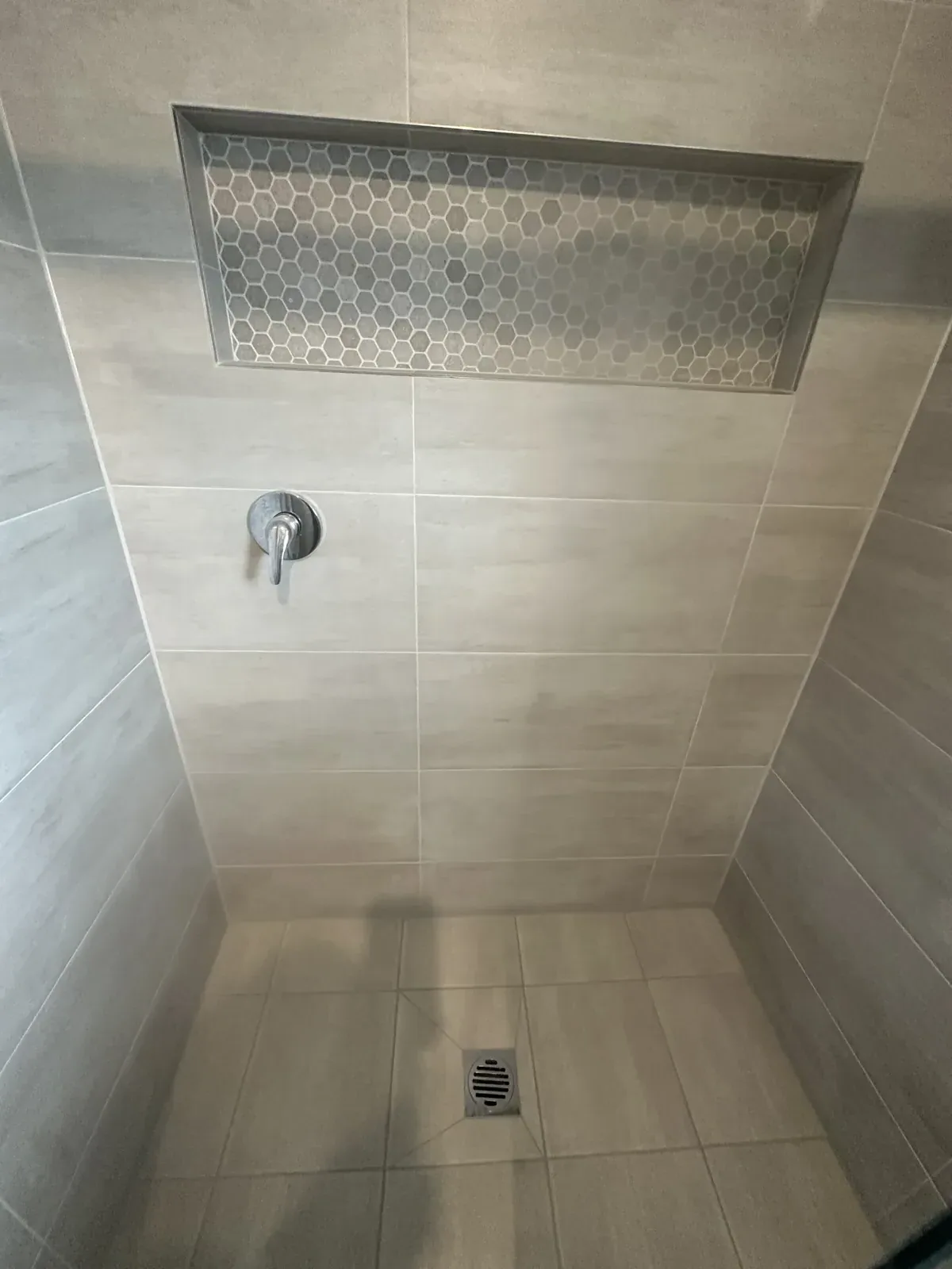 Sealed shower in grey tiles with a tiled feature niche