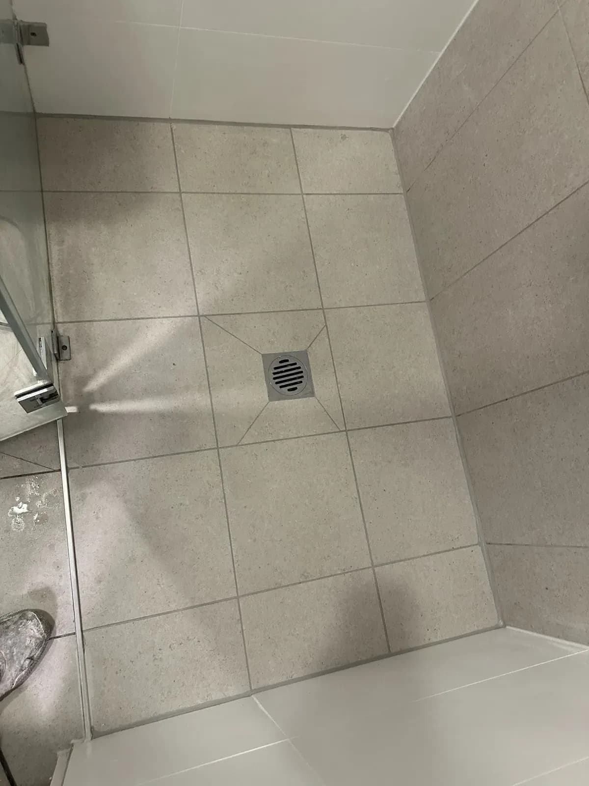 Sealed shower with grey floor tiles and a linear drain