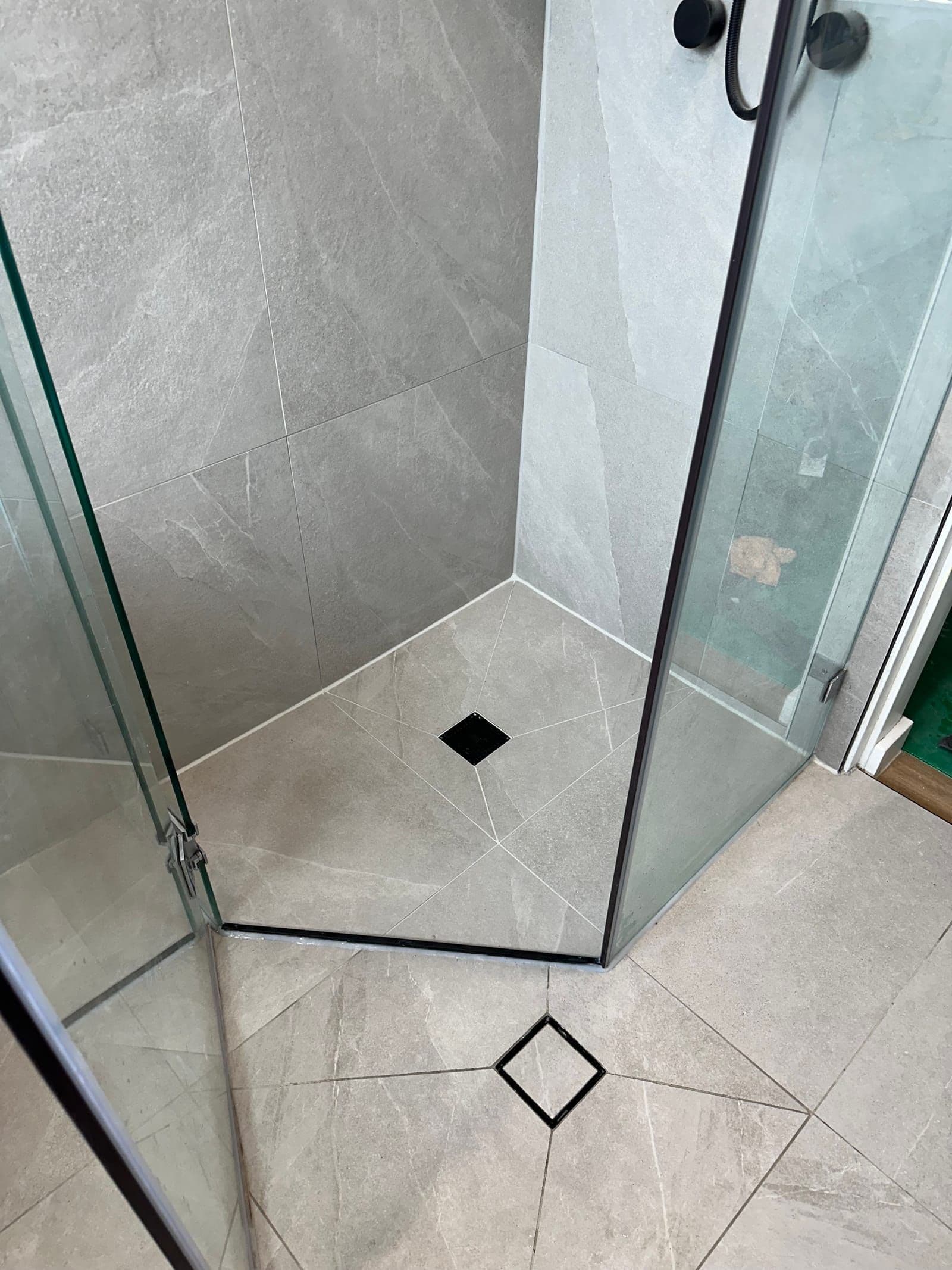 Sealed shower in large-format stone-look tiles with matte black fittings