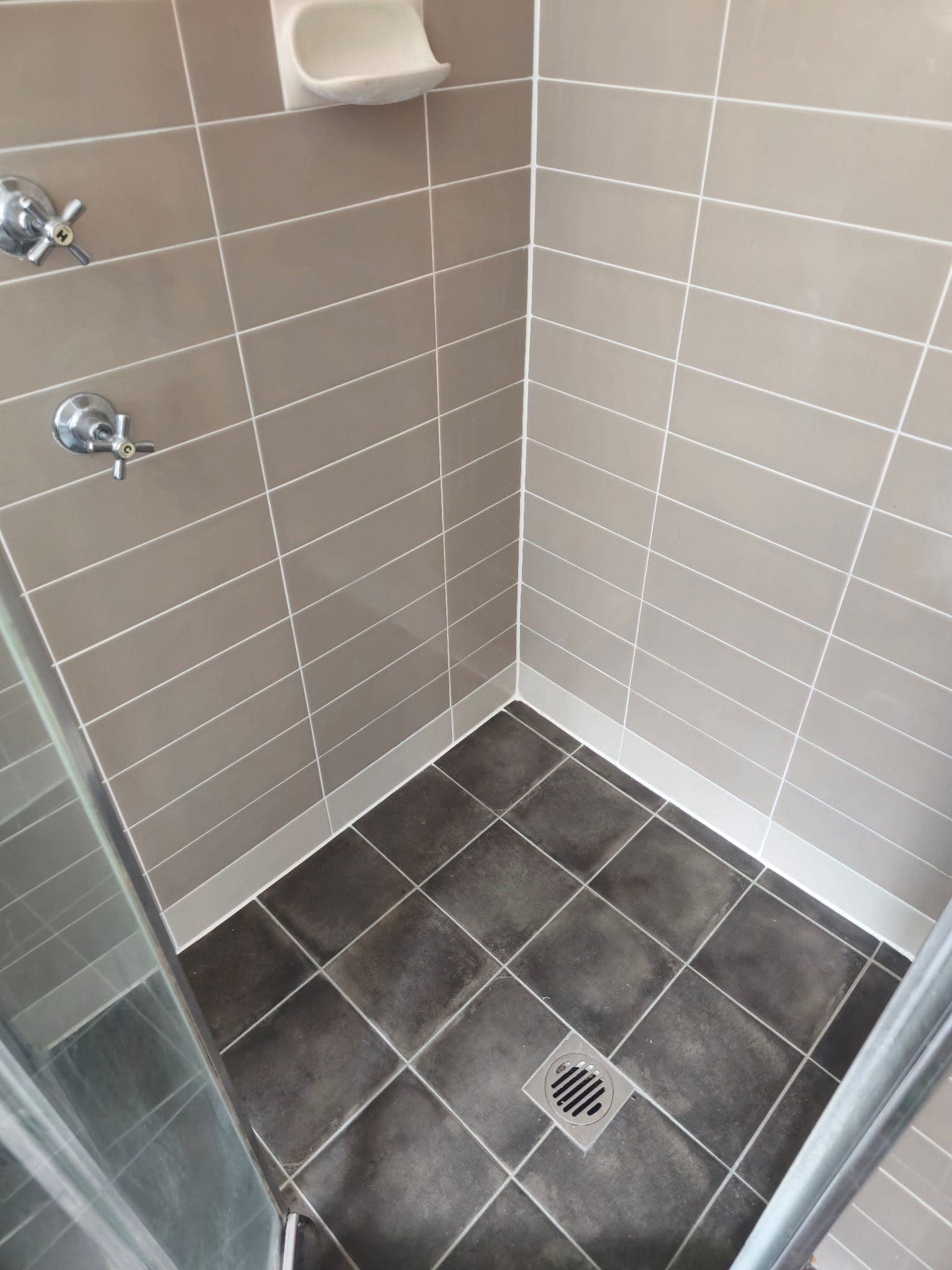 Epoxy re-grouted shower with taupe walls and a charcoal floor