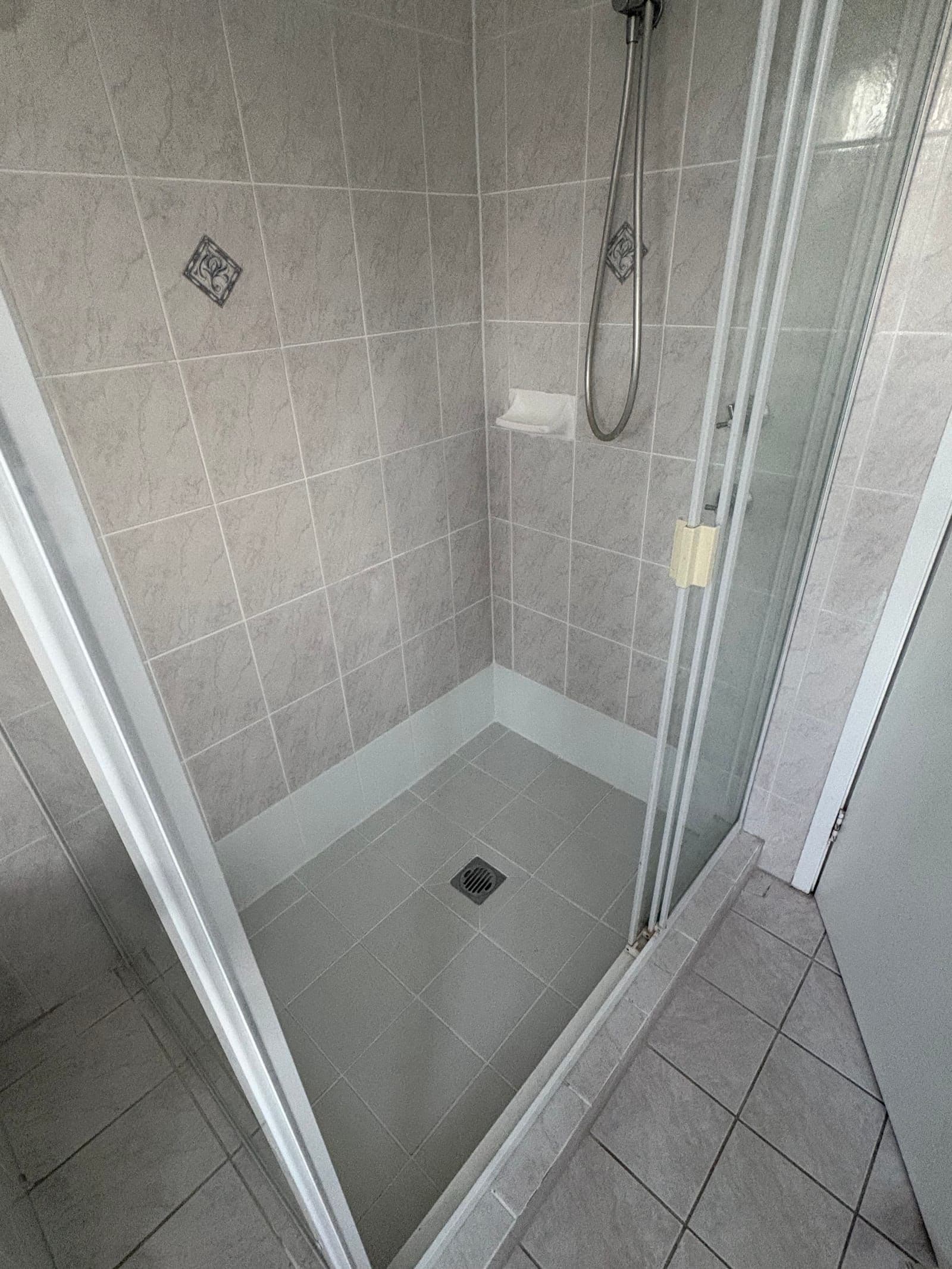 Sealed shower with grey marble-effect wall tiles and crisp grout lines