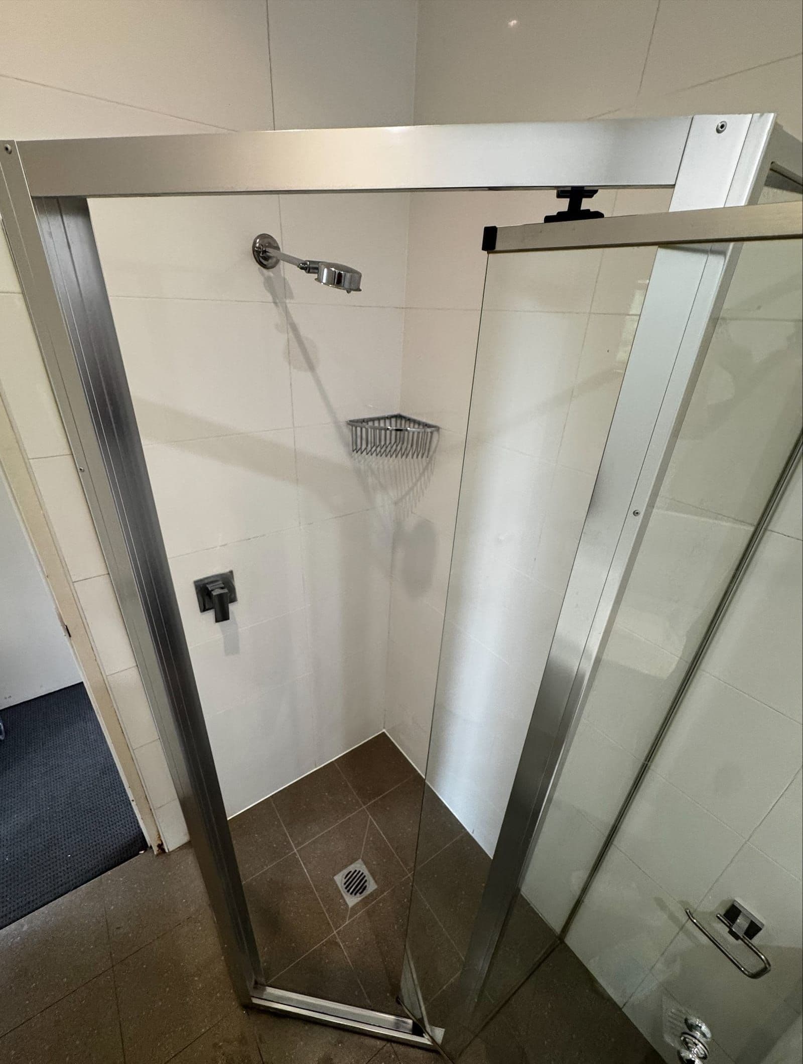 Sealed white-tiled shower with a frameless glass screen