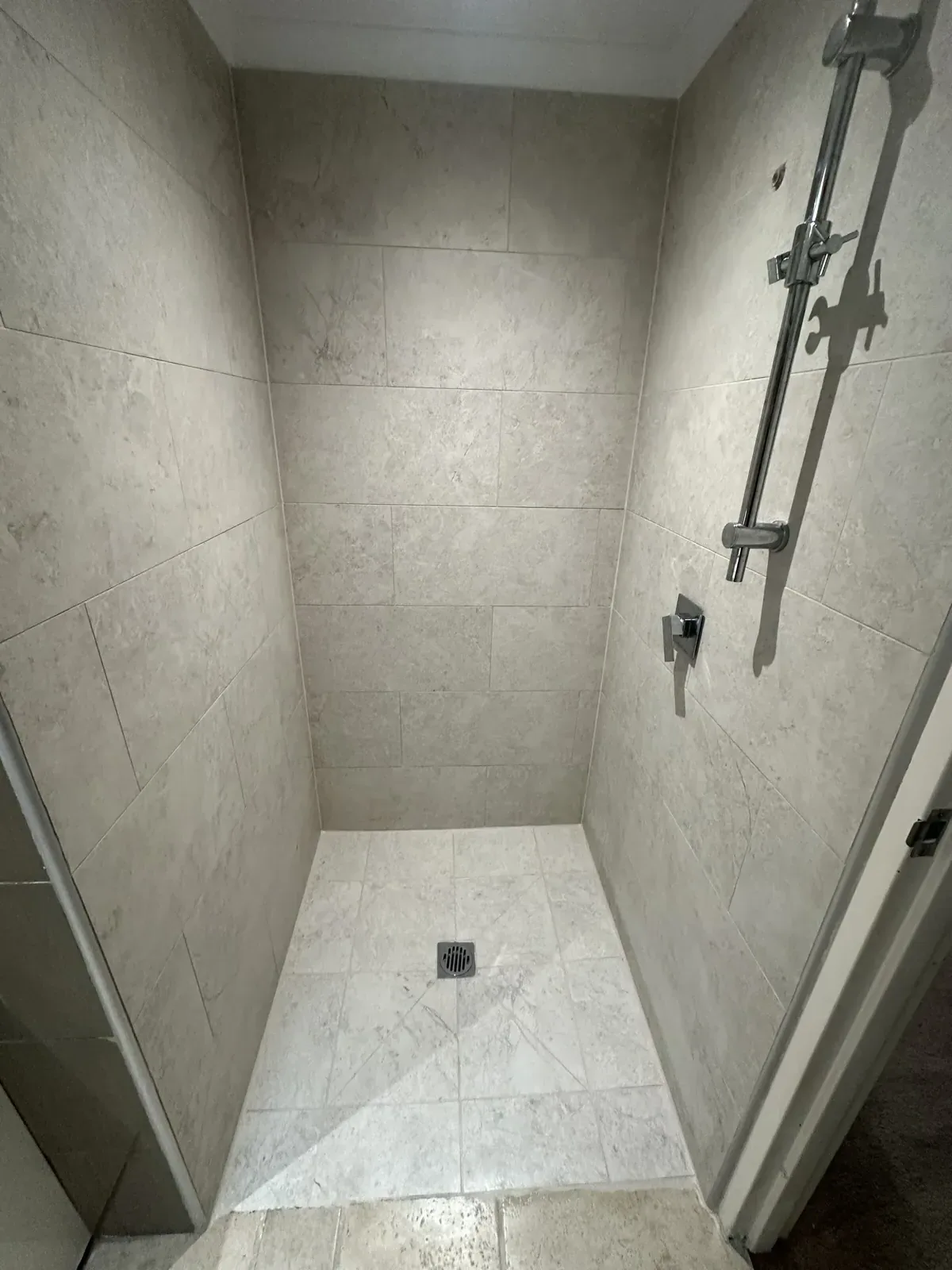 Sealed shower in stone-look tiles with a recessed shelf